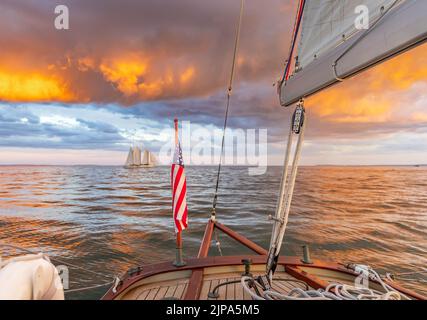 Segeln auf einem kleinen Segelboot mit Blick auf einen unglaublichen Sonnenuntergang und ferne Segelboot Stockfoto
