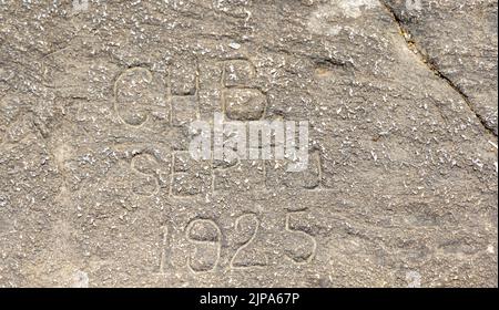 Datum und Einsticker wurden auf einem kahlen Felsberg in einen großen Felsen gemeißelt Stockfoto