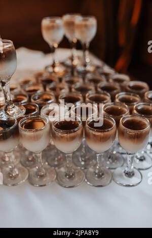 Catering. Getränke auf Hochzeitsfeier. Cocktailgläser mit rotem Alkohol stehen auf dem Tisch. Schöne Reihe von verschiedenen farbigen Alkohol-Cocktails mit Stockfoto