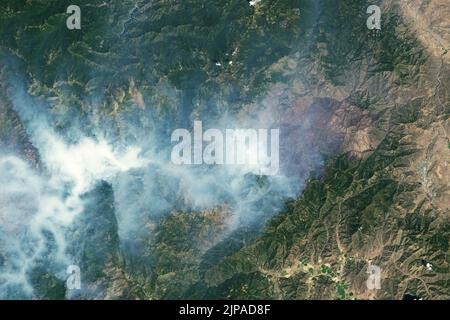 McKinney, Kalifornien, USA. 6. August 2022. Mehr als eine Woche nach seiner Entzündung brannte das Feuer von McKinney weiter durch den Klamath National Forest in Nordkalifornien. Es war 2022 der größte und tödlichste Wildlandbrand des Landes. Die vernarbte Landschaft und der Rauch von aktiv brennenden Bränden sind in den Bildern oben zu sehen. Die Aufnahmen wurden am 6. August 2022 vom Operational Land Imager (OLI) auf Landsat 8 aufgenommen. Das Falschfarbenbild (rechts) wurde aus Kurzwellen-Infrarot, Nahinfrarot und grünem Licht zusammengesetzt. Diese Band-Kombination (6-5-3) schneidet durch den Rauch, um BU zu enthüllen Stockfoto