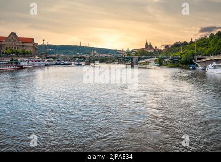 Prag, Tschechische Republik - Juni 2022: Wunderschöne Aussicht bei Sonnenuntergang mit der Cech-Brücke (Cechuv Most) von der Moldau mit der Prager Burg in der Ferne. Stockfoto