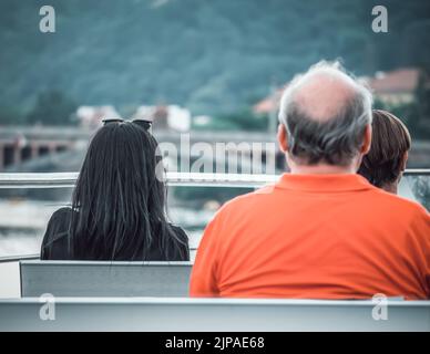 Rückansicht mit drei Personen, die sich hinsetzen. Stockfoto