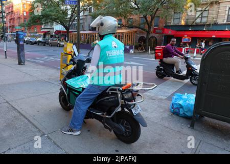 Fantuan Delivery und Grubhub Delivery Workers on Electric Mopeds in Manhattans East Village Nachbarschaft, New York City. 飯糰外賣 Food Delivery Gig Arbeiter. Stockfoto