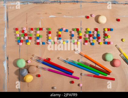 Zahlen Perlen bilden Wort Willkommen, Bleistifte und Macarons Cookies auf Holzschreibtisch. Zurück zum Schulkonzept. Stockfoto