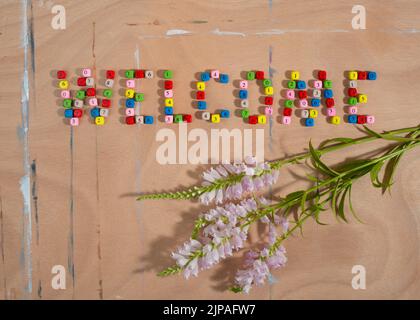 Willkommenswort aus Zahlperlen und Blumen auf Holzhintergrund. Zurück zum Schulkonzept. Stockfoto