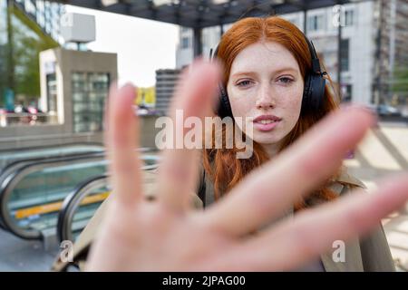 Teen Rotschopf Mädchen trägt Kopfhörer Blick auf die Kamera auf der Stadt Straße. Stockfoto