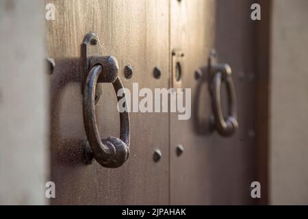 Alte Holztüren mit Ringen und altmodischer Klopfgriff aus vintage Stahl aus nächster Nähe. Stockfoto
