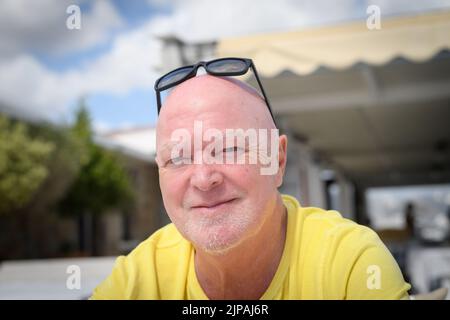 Eine Nahaufnahme eines alten kaukasischen Mannes, der im Hinterhof seines Hauses sitzt Stockfoto