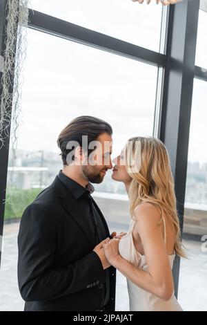 Seitenansicht eines romantischen Paares, das lächelte, während es sich im Restaurant küsste Stockfoto