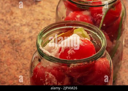 Der Prozess der Konservierung von Tomaten für den Winter. Reife rote saftige Tomaten in Glasgefäßen. Stockfoto