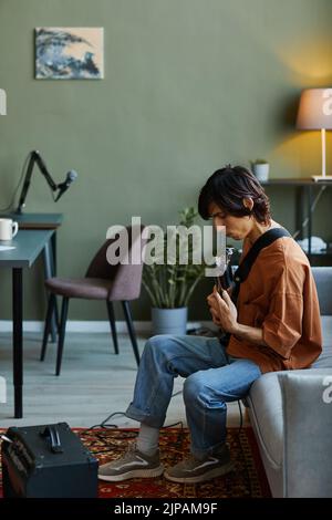 Vertikale Seitenansicht Porträt eines jungen Mannes, der in einem Heimstudio E-Gitarre spielt Stockfoto