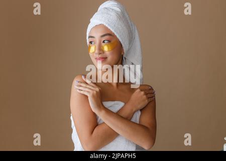 Asiatische Frau mit Masken unter den unteren Augenlidern im Studio stehen Stockfoto