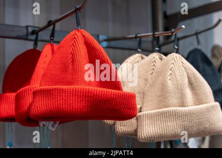 Rote und beige modische Strickmützen im Regal im Laden Stockfoto