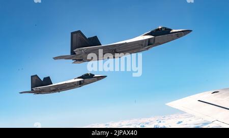 Lask, Polen. 10. August 2022. Die F-22 Raptor-Kampfflugzeuge der US Air Force, die dem 90. Fighter Squadron zugewiesen wurden, fliegen in Formation neben einem KC-135 Stratotanker-Tankflugzeug während einer NATO-Luftabschirmmission am 10. August 2022 über Lask, Polen. Kredit: SSGT. Kevin Long/USA Air Force/Alamy Live News Stockfoto