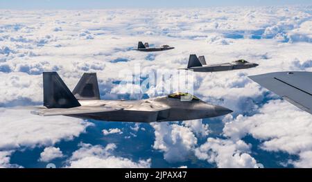 Lask, Polen. 10. August 2022. Die F-22 Raptor-Kampfflugzeuge der US Air Force, die dem 90. Fighter Squadron zugewiesen wurden, fliegen in Formation neben einem KC-135 Stratotanker-Tankflugzeug während einer NATO-Luftabschirmmission am 10. August 2022 über Lask, Polen. Kredit: SSGT. Kevin Long/USA Air Force/Alamy Live News Stockfoto