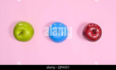 Grüne, rote und blaue Äpfel auf pastellrosa Hintergrund. Kreatives, farbenfrohes und gesundes Lifestyle-Konzept. Flach legen minimal Stockfoto