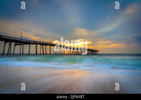 Spüren Sie die Ruhe und den Frieden, wenn die Sonne über dem Atlantischen Ozean hinter dem Fischerpier in Avon, NC, auf Hatteras Island aufgeht. Stockfoto