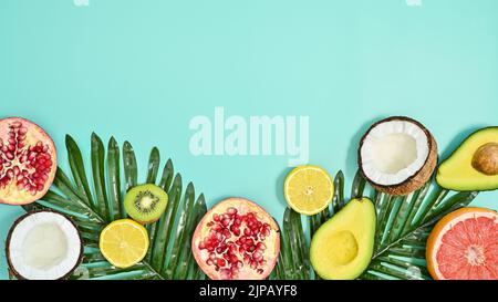Sommer tropisch Früchte und Palmblätter Anordnung auf pastellfarbenem cyanfarbenem Hintergrund. Flach liegend. Exotisches Konzept. Speicherplatz kopieren Stockfoto