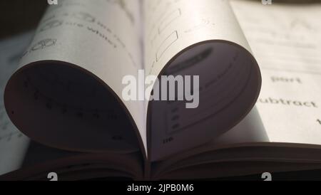 Nahaufnahme einer mathematischen Arbeitsmappe mit gefalteten Seiten, die ein Herz erzeugen Stockfoto