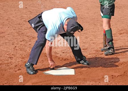 Mädchen Jugend und Trainer auf Sportplätzen während des Frühjahrssports, trainiert und Spiele spielen, Umpire reinigt die Heimbasis Stockfoto