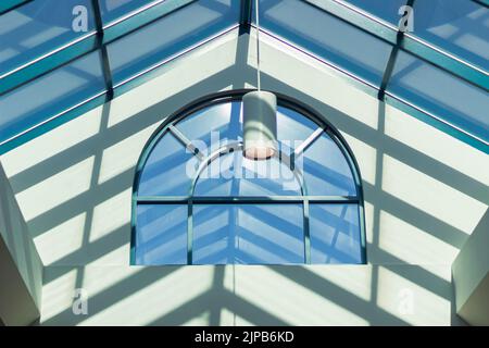 Modernes Loft-Innendesign. Sonnenstrahlen und großes Bogenfenster. Oberlicht, abstrakt. Niemand, selektiver Fokus. Licht und Schatten Stockfoto