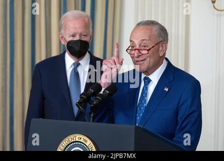 Der Mehrheitsführer des Senats der Vereinigten Staaten, Chuck Schumer (Demokrat von New York), macht Bemerkungen, während US-Präsident Joe Biden sich vor der Unterzeichnung des H.R. 5376, des Inflationsminderungsgesetzes von 2022, im State Dining Room des Weißen Hauses in Washington, DC am Dienstag, dem 16. August 2022, mit einem Blick darauf beschäftigt. Das Gesetz soll die Kosten für Energie, verschreibungspflichtige Medikamente und andere Gesundheitsfürsorge für amerikanische Familien senken, die Klimakrise bekämpfen, das Defizit verringern und die größten Unternehmen Steuern zahlen lassen.Kredit: Ron Sachs/CNP /MediaPunch Stockfoto