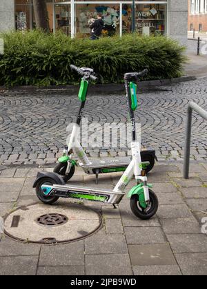 Eine vertikale Aufnahme von zwei Limone-Elektrorollern, die auf der Straße geparkt wurden Stockfoto