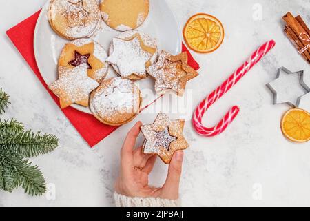 Traditionelle Weihnachts-linzer-Kekse. Feminine Hand mit Keks, Draufsicht Stockfoto