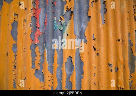 Orangefarbene und rote abblätternde Farbe auf Wellblechverkleidung. Stockfoto