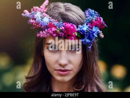 Blumenkrone für eine Königin der Natur. Porträt einer schönen jungen Frau, die einen Blumenkranz im Freien trägt. Stockfoto