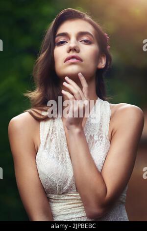 Lassen Sie sich von ihrer Schönheit verzaubern. Eine schöne junge Frau, die in der Natur posiert. Stockfoto