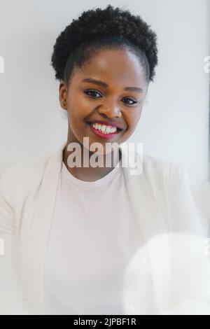 Lächelnde, attraktive afroamerikanische Geschäftsfrau, die direkt in die Kamera schaut. Konzept des Modells, erfolgreicher Unternehmer Stockfoto
