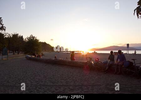 Menschen beobachten den Sonnenuntergang am Strand von Spanish Banks in Vancouver, BC, Kanada. Stockfoto