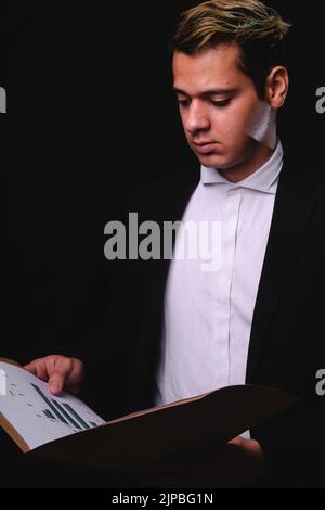 Business blonde Mann Überprüfung Papiere in einer Aktentasche. Geschäftsleiter liest wichtige Papiere. Mann im schwarzen Anzug mit weißem Hemd. Hochwertige Fotos Stockfoto