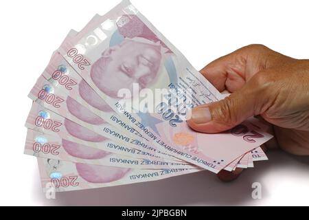 Älterer Mann faltete Hände, die türkische Lira-Banknoten auf weißem Hintergrund hielten.Krisenkonzept der Finanzwährung. Stockfoto