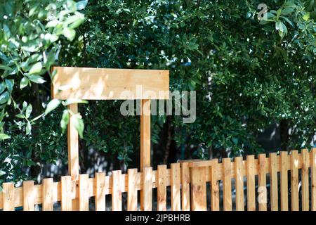 Mitten in einem grünen Baumgarten steht ein neues Holzschild Stockfoto