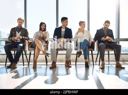 Ich denke, es ist nicht der einzige, der nach Erfolg hungert: Eine Gruppe von Geschäftsleuten, die eine Pause machen, während sie in einem Büro anstehen. Stockfoto