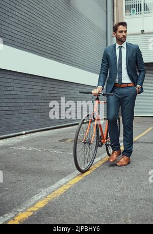 Tut seinen Teil, um eine sauberere Fußabdruck zu hinterlassen. Ein hübscher junger Geschäftsmann steht neben seinem Fahrrad im Freien. Stockfoto