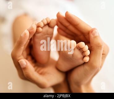 Die winzigen Füße, die ihr Leben vollendet haben. Eine Mutter hält ihre Babys sanft an den Füßen. Stockfoto