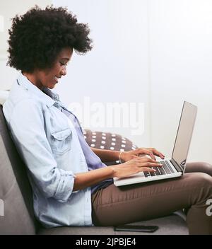 Arbeiten an etwas, das ihre Blog-Follower lieben werden. Eine junge Frau, die zu Hause einen Laptop auf dem Sofa benutzt. Stockfoto