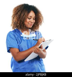 Sie achtet sorgfältig auf jede Patientenakte. Studioaufnahme einer attraktiven jungen Krankenschwester, die auf einem Klemmbrett vor weißem Hintergrund schreibt. Stockfoto