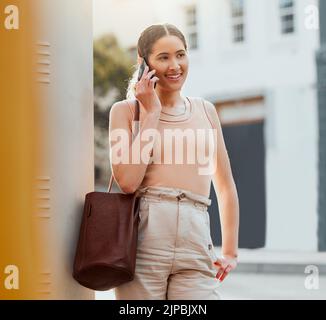 Zwanglose Frau, die allein in der Stadt steht und telefoniert, Networking unterhält und Gespräche führt. Trendy, lächelnd und fröhlich weiblich Stockfoto