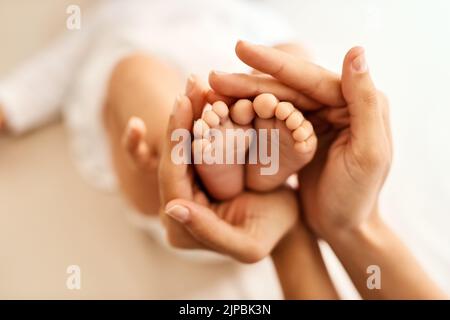 Nichts süßlicheres als kleine Babyfüße. Eine Mutter hält ihre Babyfüße sanft. Stockfoto