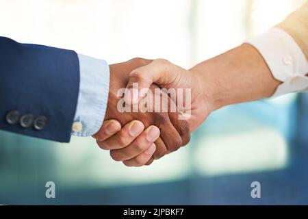 Zwei Geschäftsleute, die sich in einem modernen Büro die Hände schütteln. Stockfoto