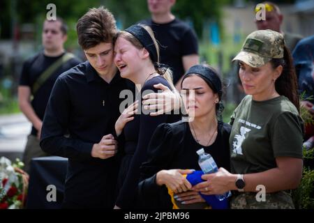 Kiew, Ukraine. 18.. Juli 2022. Angehörige reagieren emotional während der Beerdigungszeremonie eines ukrainischen Soldaten mit dem Spitznamen „Fanat“ in Kiew. Ein Soldat wurde in einer Schlacht in der Ostukraine infolge der russischen Invasion in der Ukraine getötet. Die Angehörigen des Soldaten halten seinen Namen und sein Foto geheim, weil das Leben seines Vaters in einem Teil der von russischen Truppen besetzten Region Luhansk in Gefahr sein wird und wenn die Besatzungsbehörden herausfinden, dass sein Sohn in der ukrainischen Armee gekämpft hat, kann der Vater verhaftet und gefoltert werden. (Bild: © Oleksii Chumachenko/SOPA Images via ZUMA Press Wire) Stockfoto