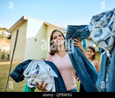 Meine Familie verdient jeden Tag saubere Kleidung. Porträt einer Mutter und Tochter, die draußen ihre Wäsche aufhängen. Stockfoto