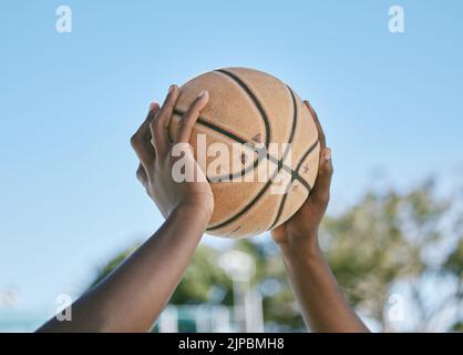 Basketball, Sport und Spiel mit einem Ball in den Händen eines Spielers, Athleten oder Profisportlers. Nahaufnahme eines Spiels oder Spiels draußen auf einem Stockfoto