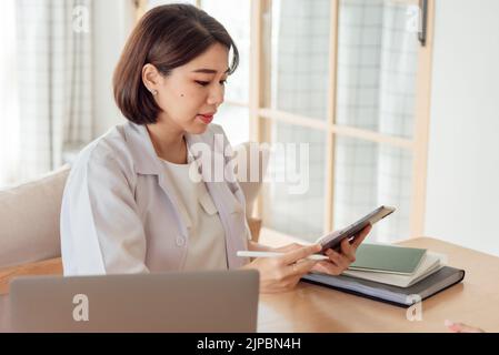Eine Ärztin verwendet eine Tablette, um die Symptome eines Patienten im Büro zu analysieren. Stockfoto