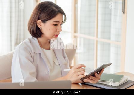 Eine Ärztin verwendet eine Tablette, um die Symptome eines Patienten im Büro zu analysieren. Stockfoto