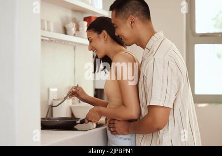 Romantisches, liebevolles und fürsorgliches Paar Kochen und Bonding während Umarmung am Morgen zu Hause. Lächelnder Ehemann und Ehefrau halten sich gegenseitig und umarmen sich Stockfoto